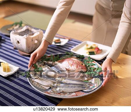 Stock Photo - Woman holding plate of various fish. Fotosearch