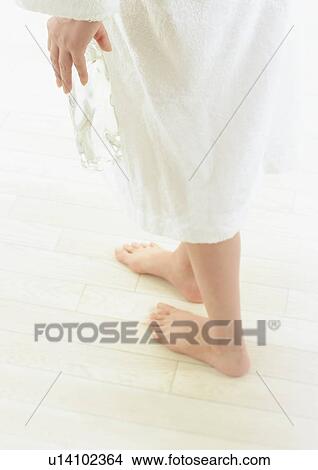 Picture - Woman in bath robe holding bottled water. Fotosearch