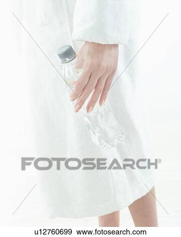 Stock Photo - Woman in bath robe holding bottled water. Fotosearch