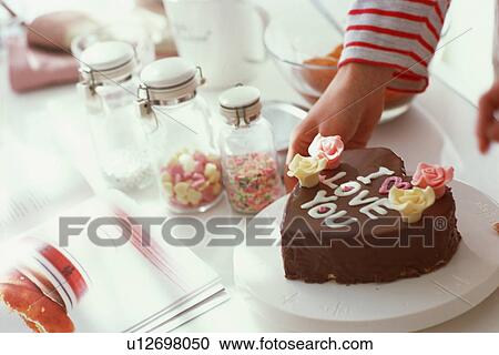 Stock Image - Woman preparing chocolate Valentine's Day cake. Fotosearch