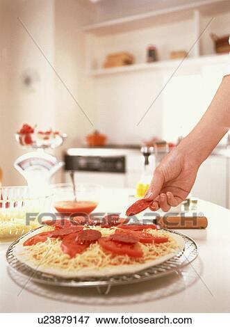 Stock Photo - Woman preparing tomato and pepperoni pizza. Fotosearch