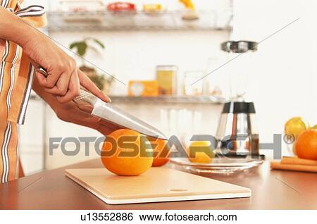 Woman slicing orange on cutting board View Large Photo Image Stock Photograph - Woman slicing orange on cutting board. Fotosearch