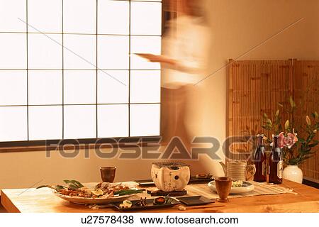 Stock Photo - Woman walking past table with Japanese food. Fotosearch
