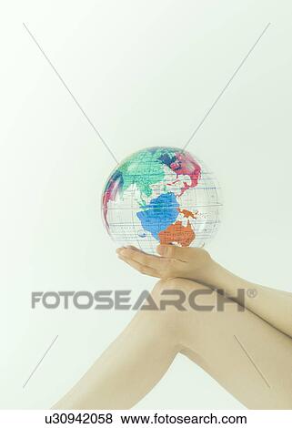 Stock Photo - Women's hands holding a world map beach ball. Fotosearch