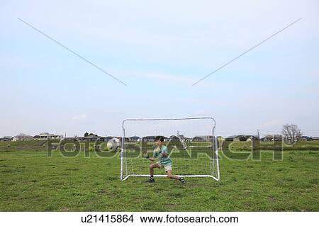 Picture - Young boy goalkeeping on field. Futako-tamagawa, Setagaya-ku, Tokyo Prefecture, Japan. Fotosearch
