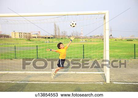 Stock Image - Young boy goalkeeping on field. Futako-tamagawa, Setagaya-ku, Tokyo Prefecture, Japan. Fotosearch