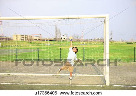 Stock Photography - Young boy goalkeeping on field. Futako-tamagawa, Setagaya-ku, Tokyo Prefecture, Japan. Fotosearch