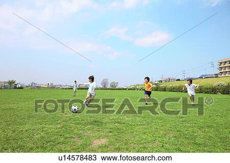 Stock Image - Young boys playing soccer on field. Futako-tamagawa, Setagaya-ku, Tokyo Prefecture, Japan. Fotosearch