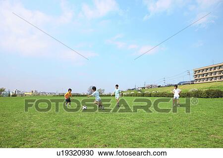 Stock Image - Young boys playing soccer on field. Futako-tamagawa, Setagaya-ku, Tokyo Prefecture, Japan. Fotosearch