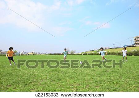 Stock Image - Young boys playing soccer on field. Futako-tamagawa, Setagaya-ku, Tokyo Prefecture, Japan. Fotosearch