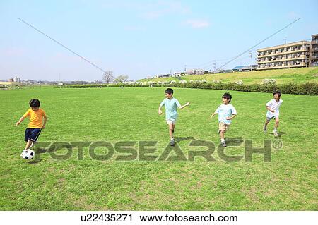 Stock Image - Young boys playing soccer on field. Futako-tamagawa, Setagaya-ku, Tokyo Prefecture, Japan. Fotosearch