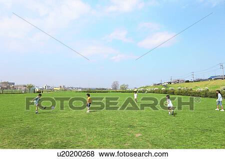 Stock Photo - Young boys playing soccer on field. Futako-tamagawa, Setagaya-ku, Tokyo Prefecture, Japan. Fotosearch