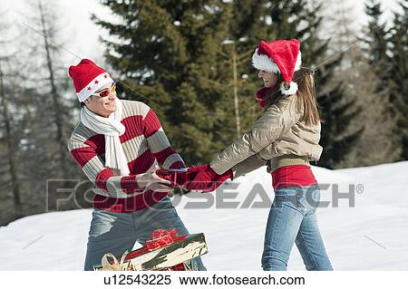 Stock Photography - Couple in Christmas outfit, holding a present. Fotosearch