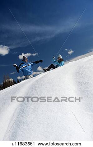 Stock Image - Couple in snow, young man throwing snowball. Fotosearch