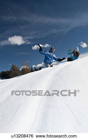 Stock Photograph - Couple in snow, young man throwing snowball. Fotosearch