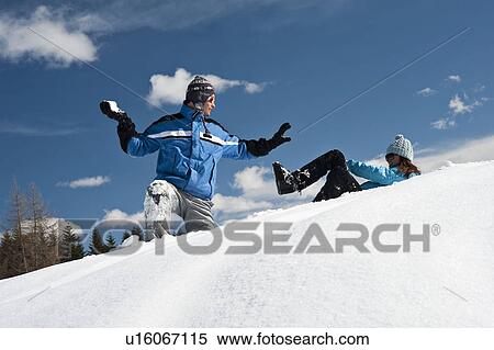 Stock Photography - Couple in snow, young man throwing snowball. Fotosearch
