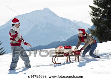 Stock Photo - Couple with sleigh and presents in winter scene. Fotosearch