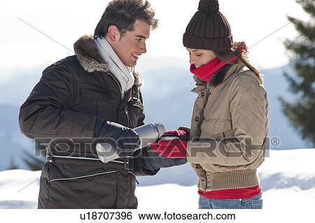Young man pouring from thermos into young woman's cup in winter scene View Large Photo Image Stock Photograph - Young man pouring from thermos into young woman's cup in winter scene. Fotosearch