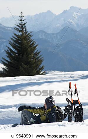 Young man sitting in snow with hiking gear View Large Photo Image Stock Image - Young man sitting in snow with hiking gear. Fotosearch