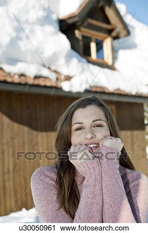 Stock Image - Young woman in front of ski lodge. Fotosearch