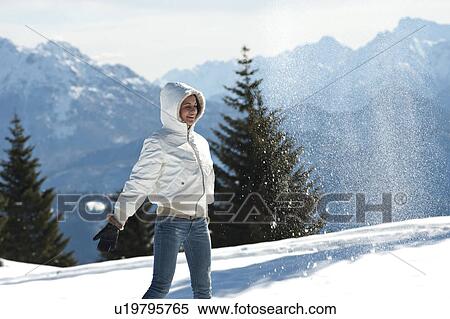 Stock Photography - Young woman in winter scene with snow spray, arms outstretched. Fotosearch