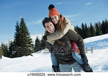 Stock Photography - Young woman riding piggyback on young man in winter scene. Fotosearch