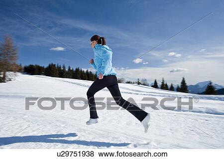 Stock Photo - Young woman running in snow. Fotosearch