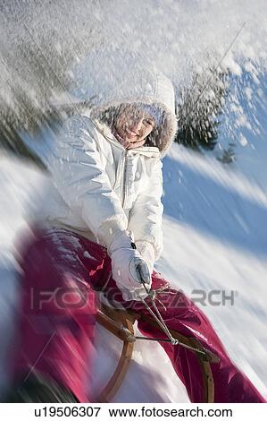 Stock Photo - Young woman sledding. Fotosearch