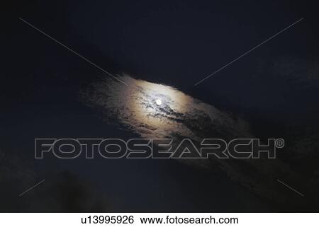 Stock Photograph - A full moon emerging from behind clouds. Fotosearch
