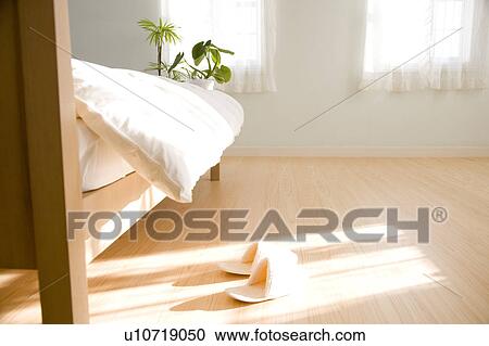 Stock Image - A pair of slippers next to bed. Fotosearch