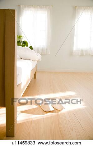 Stock Image - A pair of slippers next to bed. Fotosearch
