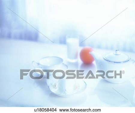 Picture - A tea set, an orange and a glass of milk. Fotosearch