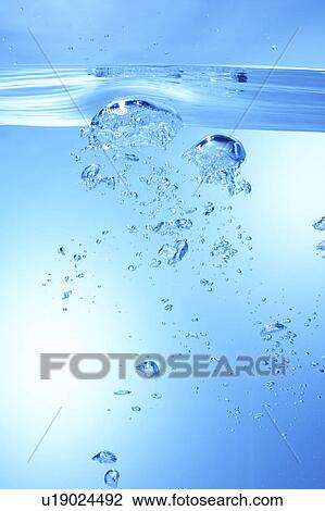 Stock Image - Air bubbles in water, close up, blue background. Fotosearch