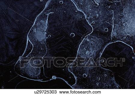 Stock Image - Air bubbles trapped beneath icy surface. Fotosearch