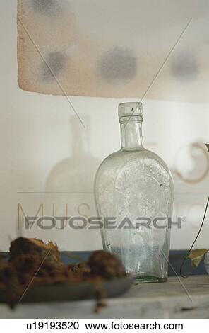 Stock Image - Antique glass bottle with plate of food. Fotosearch