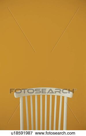 Stock Photo - Back of a white chair against yellow wall. Fotosearch