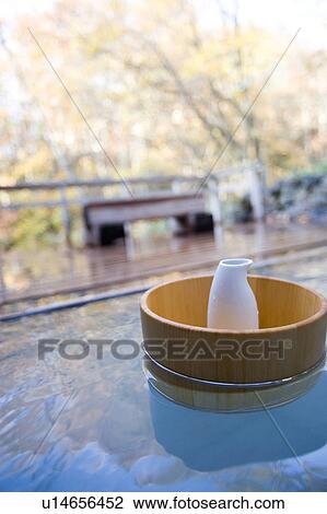 Stock Image - Bamboo bucket containing a saki decanter in a hot spring. Fotosearch