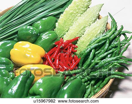 Stock Image - Basket of chilies, peppers and bitter melons. Fotosearch