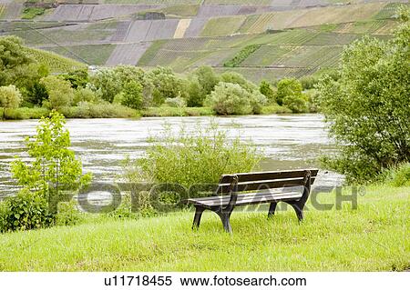 Stock Photography - Bench by the Mosel River with a Vineyard in the distance, Moselle, Germany. Fotosearch