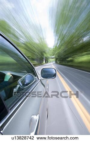 Stock Image - Car driving along a tree lined road. Fotosearch