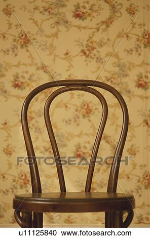 Stock Image - Chair against patterned wallpaper. Fotosearch