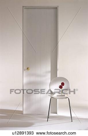 Stock Image - Chair by a door with red flowers on it. Fotosearch