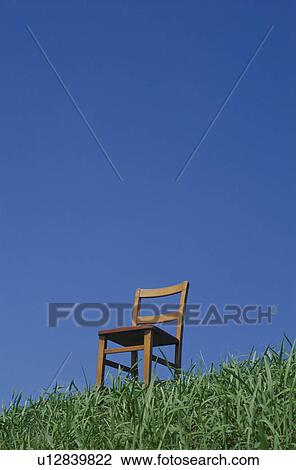 Stock Image - Chair in meadow against blue sky. Fotosearch