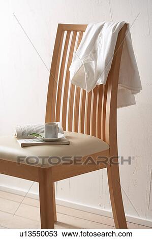 Stock Image - Chair with coffee cup, book and shirt. Fotosearch