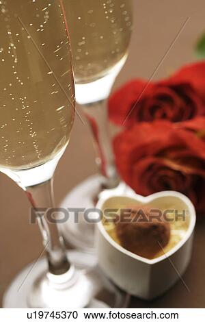 Stock Image - Champagne glasses, roses and a gift box of truffles. Fotosearch