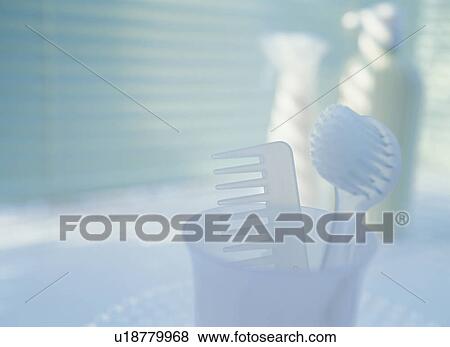 Stock Photo - Comb and brush in a container in a bathroom. Fotosearch