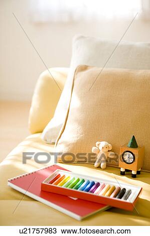 Stock Image - Crayon and notepad on sofa. Fotosearch