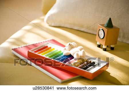 Stock Image - Crayon and notepad on sofa. Fotosearch