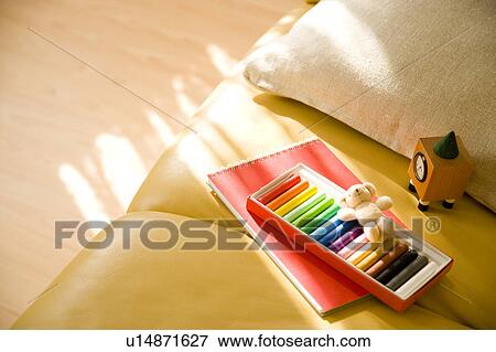 Stock Photo - Crayon and notepad on sofa. Fotosearch
