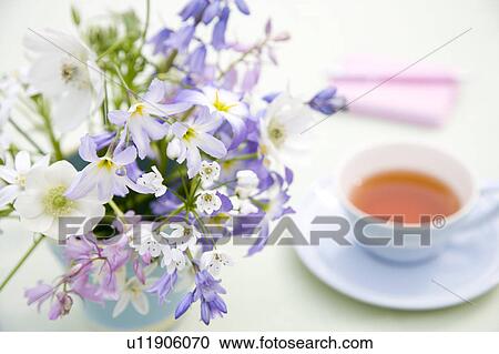 Stock Image - Cup of tea and bunch of flowers. Fotosearch